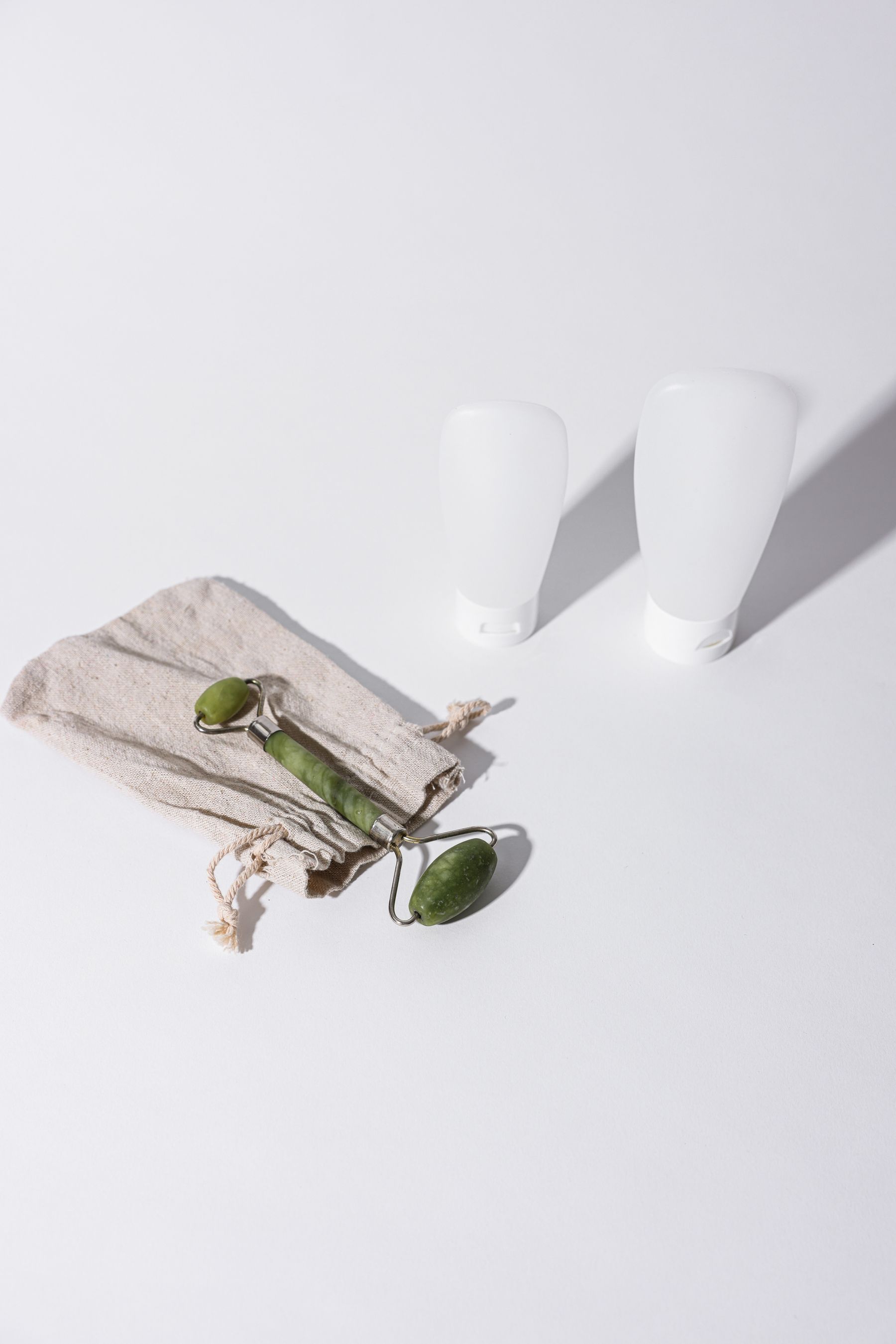 Unbranded white skincare containers with a jade facial roller