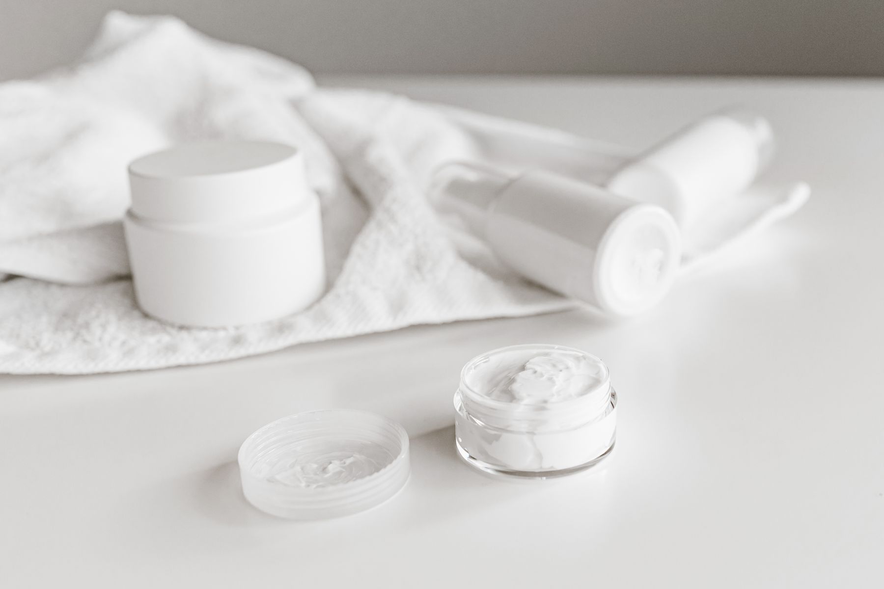 Unbranded white skincare jars and tubes on a clean surface